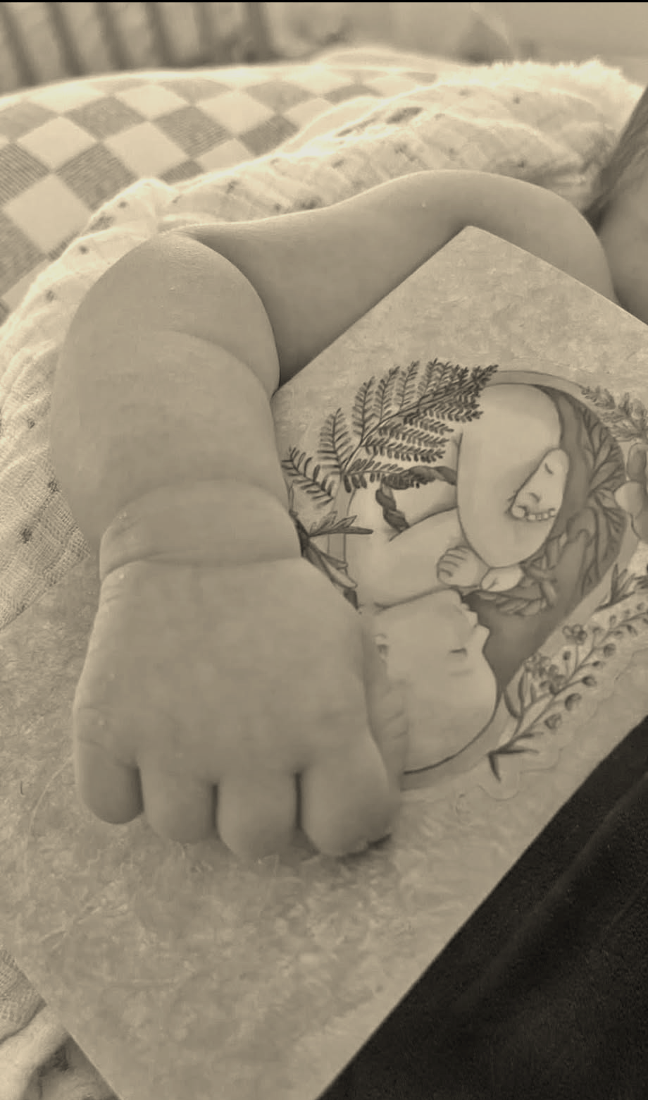 Main d'un nouveau-né posée sur un carnet de naissance illustré