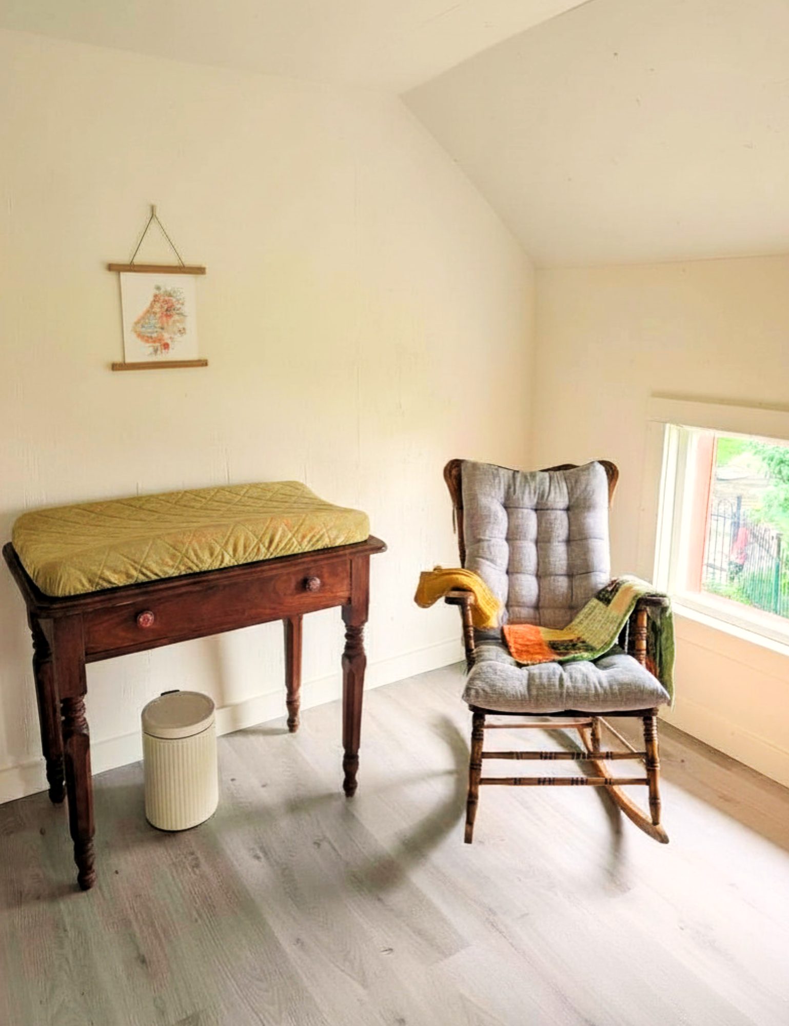 Coin soin avec table à langer et chaise berçante près de la fenêtre